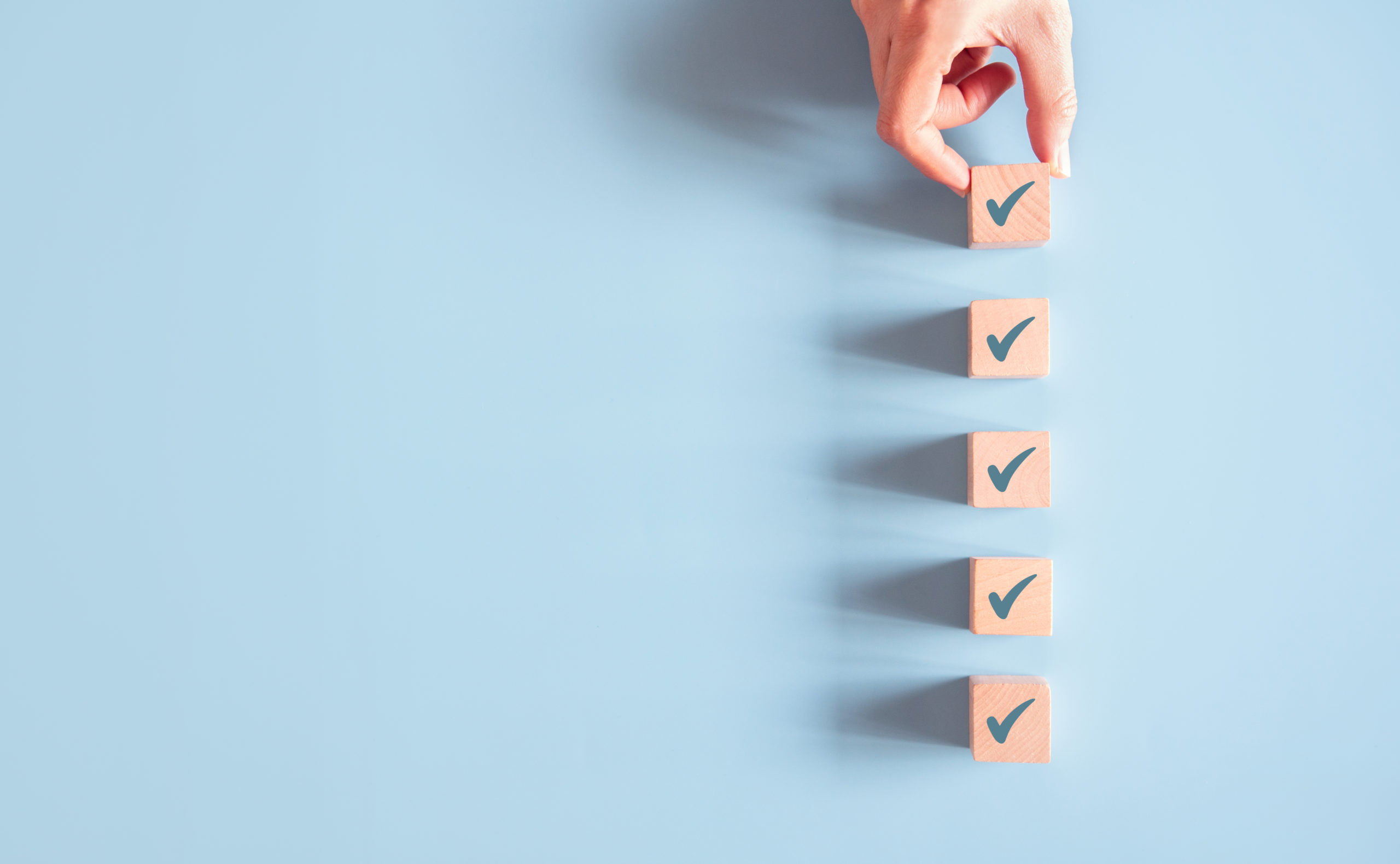 Wood cube with check mark on blue background, Checklist concept, Copy space.